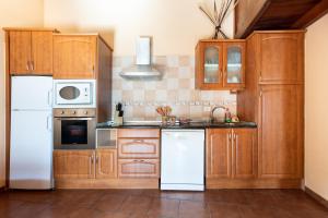 El Pinar del HierroHome2Book Charming Rustic House El Pinar & Wifi的厨房配有木制橱柜和白色家电
