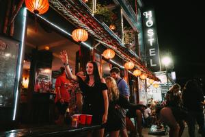 顺化越南背包客旅舍 - 顺化的站在酒吧的女人,手放在空中
