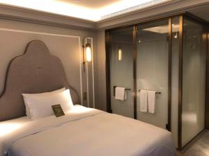 杭州杭州西湖美居酒店的卧室配有白色的床和淋浴