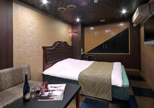 四日市Hotel Mio Resort ( Adult Only)的酒店客房配有床、桌子和沙发。