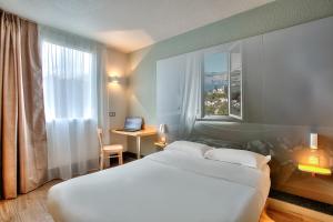 比奥B&B HOTEL Antibes Sophia Antipolis的酒店客房配有一张床、一张书桌和一台笔记本电脑