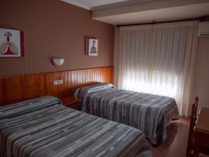 托雷利亚诺Hostal Durá的酒店客房设有两张床和窗户。