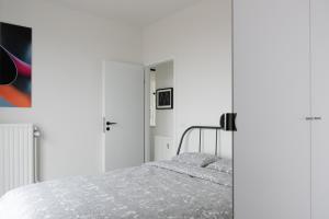 布兰肯贝赫Unieke Penthouse bij Brugge的一间白色卧室,配有一张床和一个衣柜