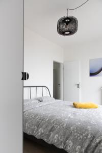 布兰肯贝赫Unieke Penthouse bij Brugge的白色卧室配有一张床和一个吊灯