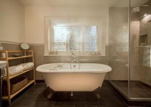 Hurley赫利之家酒店的带浴缸和玻璃淋浴间的浴室。