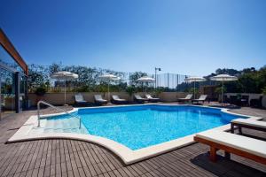卡利亚里卡利亚里假日酒店的一座大楼内的游泳池,配有椅子和遮阳伞