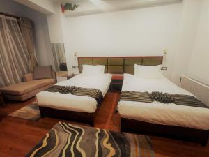 廷布Ludrong Hotel的酒店客房,设有两张床和一张沙发