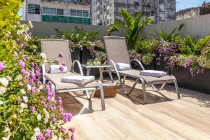 布宜诺斯艾利斯Huinid Obelisco Hotel的庭院里种着鲜花,配有两把椅子和一张桌子