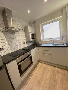 普雷斯顿6Adelphi的厨房配有白色橱柜、水槽和窗户。