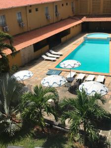 伊塔帕里卡Hotel Icaraí的享有酒店游泳池的顶部景色,设有椅子和遮阳伞