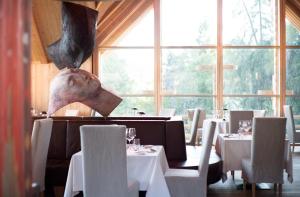 索普拉布扎诺ADLER Lodge RITTEN的餐厅设有白色的桌椅和大窗户