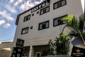 阿鲁雅Hotel Nobre Requinte的白色的建筑,上面有酒店标志