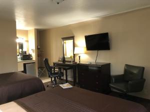 尤金Value Inn Motel EUGENE AIRPORT的酒店客房配有一张床、一张书桌和一台电视。