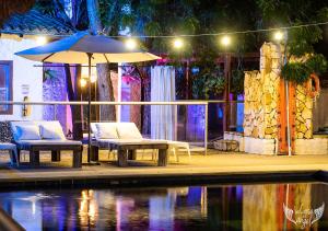 比利亚维哈Hotel Infinito La Casona的晚上泳池旁的两把椅子和一把遮阳伞