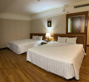 东港大鹏湾度假酒店的配有白色床单的酒店客房内的两张床