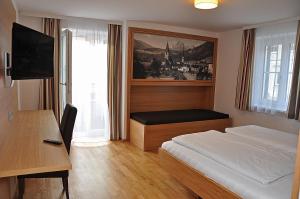 比绍夫斯霍芬格斯特霍夫蒂洛尔维特酒店的一间卧室配有一张床、一张书桌和一台电视