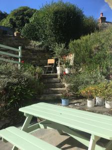 特鲁罗The Thatched Cottage的花园里的绿色野餐桌,种有盆栽植物