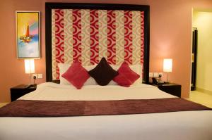塔伊夫Swiss Spirit Hotel & Suites Taif的一间卧室配有一张带红色枕头的大床