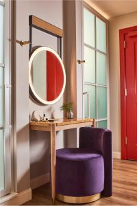 达拉斯Virgin Hotels Dallas的梳妆台、镜子和紫色椅子