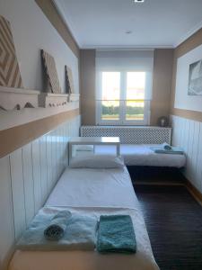 桑坦德apartamento con jardín privado y barbacoa a 5 min playas santander的小房间设有两张床和窗户