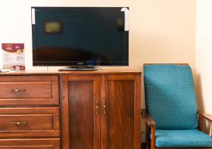 雷塔卢莱乌罗斯奎乔斯豪宅酒店的坐在木柜顶部的电视机,上面摆放着蓝色的椅子