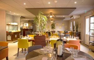 布克凡尔赛贝斯特韦斯特酒店的餐厅设有桌椅和黄色及橙色椅子