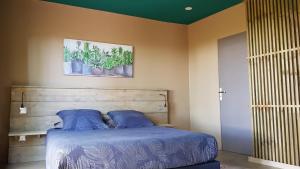 Sainte-SuzanneLe lodge origin的一间卧室配有一张带蓝色床单和植物的床。