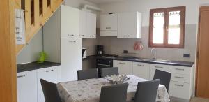 莱德罗Villa Maria Arnalda的厨房配有白色橱柜和桌椅