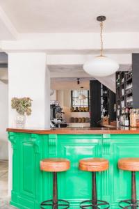托特尼斯The Bull Inn的厨房里设有绿色的酒吧,配有木凳