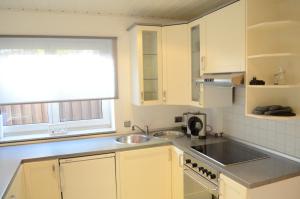 雷德斯塔德Wohnung Ahorn的厨房配有白色橱柜、水槽和窗户。