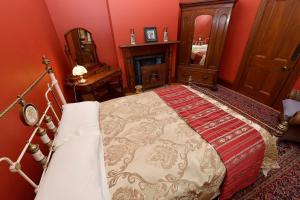 里夫顿Harold House的红色卧室设有一张床和一个壁炉