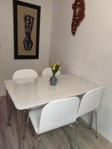 瑟沃格Apartments-BnB的一张带两把椅子的白色桌子和一个花瓶