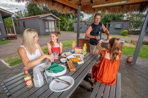阿德莱德Adelaide Caravan Park - Aspen Holiday Parks的一群人坐在野餐桌旁,吃着食物