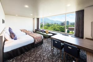 札幌MYSTAYS 札幌中岛公园酒店的酒店客房设有一张床、一张书桌和一个大窗户。