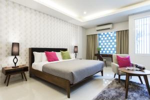 清迈Tolani Nimman Villa Chiang Mai的一间卧室配有带粉色和绿色枕头的床