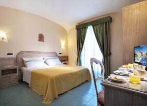 伊斯基亚皇家温泉酒店的一间卧室配有一张床和一张桌子及一台电视