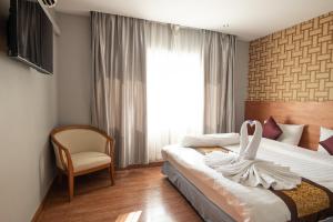 素叻CBD素拉泰尼酒店的卧室配有床、椅子和窗户。