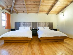 米内拉尔德尔蒙特Collection O Casona De Minas的客房设有两张床,配有木制天花板和木地板。