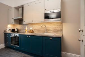 道格拉斯Amadeus Apartments的厨房配有蓝色橱柜和水槽