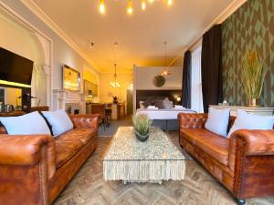 利兹The Deakin at Claremont Serviced Apartments的客厅配有真皮沙发和床。
