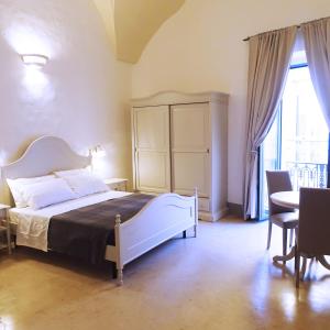 马蒂诺Le Finestre Su Porta Carrese - Luxury Rooms & Suites的卧室配有一张床和一张桌子及椅子