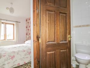 MorlandSpringarth Cottage的一间带木门的浴室和一间带一张床的卧室