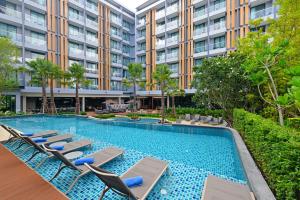 芭堤雅市中心Hotel Amber Pattaya的大楼前带躺椅的游泳池