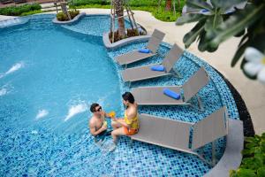 芭堤雅市中心Hotel Amber Pattaya的两人坐在度假村的游泳池里