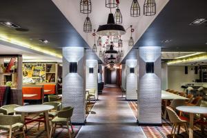 沃特福德伦敦沃特福德枢纽假日酒店的餐厅设有白色的圆柱和桌椅