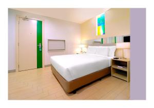 马尼拉Go Hotels Ortigas Center的卧室配有一张白色大床和一扇绿门