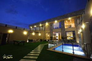 利雅德Masurat Chalet的一座晚上设有游泳池的房子