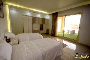 利雅德Masurat Chalet的酒店客房设有两张床和大窗户。