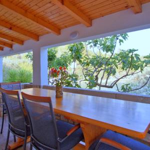 尼亚卢卡Getaway Beach House的配有大窗户的客房内的一张木桌和椅子
