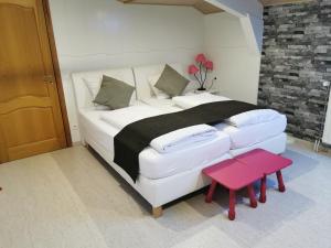 韦姆Hôtel Belair "Ravel Etape"的卧室配有一张大白色床和红色凳子